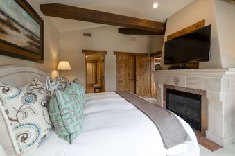 The Chateaux Luxury Three Bedroom Suite features a cozy bedroom with a large bed, a fireplace, and a TV for ultimate relaxation and comfort.