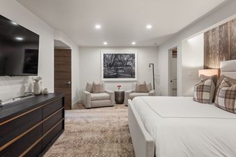 A spacious and elegantly decorated bedroom at Casa de Gondola featuring a king-sized bed, seating area, and entertainment unit.