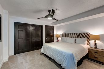 A stylish bedroom in Abode in Snow Park features a modern ceiling fan, cozy carpet, and inviting decor.
