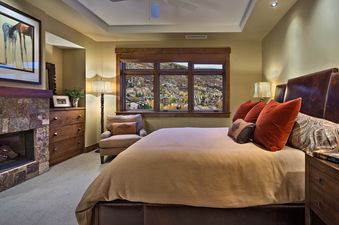 A luxurious bedroom at Sugar Loaf Mountain One Steamboat Place 703 features a comfortable bed, a cozy fireplace, and a large window offering scenic views of the surrounding area.