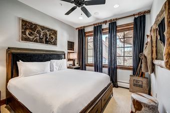 The bedroom in Bear Paw Lodge 4 Bedroom Plus Loft features a comfortable bed, ceiling fan, and large windows.