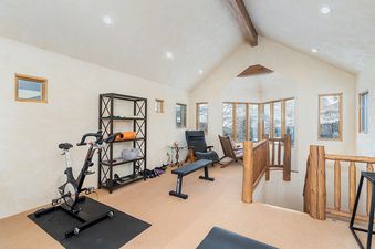 A home gym with a stationary bike, weight bench and yoga mat.