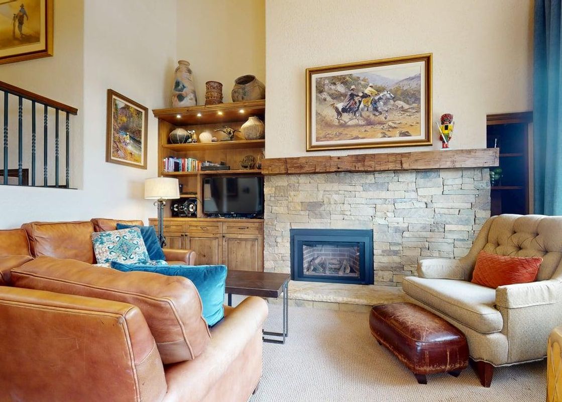 The cozy living area at Vantage Point 401 features a fireplace, leather couch, and plush armchair.