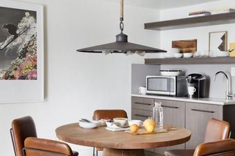 Dining table and chairs next to a small kitchenette in the Gravity Haus JH Premium Loft Suite.