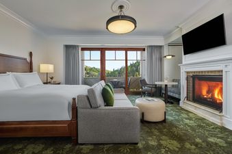 The Montage Deer Valley King Room Vista View with Fire Pit features a king-sized bed, a cozy sofa, a fireplace, and a balcony overlooking a scenic vista.