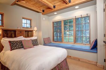The bedroom at Moonlight Basin Lodging 38A Cowboy Heaven has a king bed, a large window, and a wooden ceiling.
