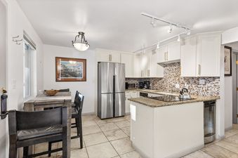 A bright and functional kitchen at Silverglo Condominiums 205 with modern appliances, white cabinets, and a dining area.