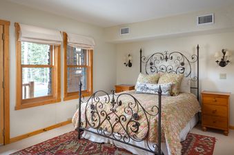 The inviting bedroom in Wild Bear Haven features a wrought iron bed frame and warm colors.