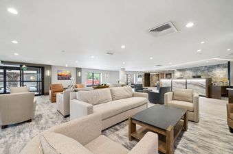 A wide shot of The Charter C1105 lobby, showing multiple seating areas with sofas and armchairs, a modern reception desk with a marble front, and stone accent walls.
