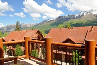 The view from Townhomes On The Creek 121's balcony showcases the surrounding mountains and log cabin architecture.