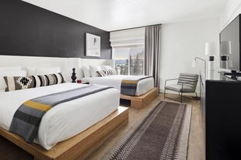 Modern bedroom with two queen beds and a black accent wall at Gravity Haus JH ADA Two Queen and Roll In.