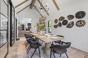 The dining area at Abode at Hollow Mountain features a light wood table with seating for six and striking tree-trunk wall art.