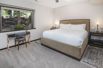 A serene bedroom at Chateau Tremonte 8 with a king-sized bed, a desk by a window with an outdoor view, and modern furnishings.