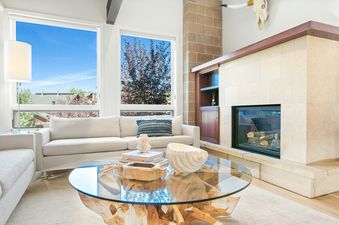 A cozy living room at Mountain Elegance 2835 features a stone fireplace, comfortable sofa, and a large glass coffee table.