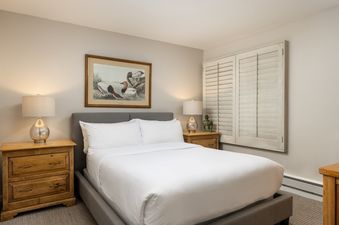 The comfortable bedroom at Montaneros 410 features a gray bed frame, white bedding, and light-colored nightstands.