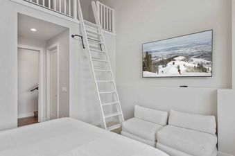Loft bedroom in SkyRidge 1307 featuring a ladder, floor seating, and a wall-mounted TV.