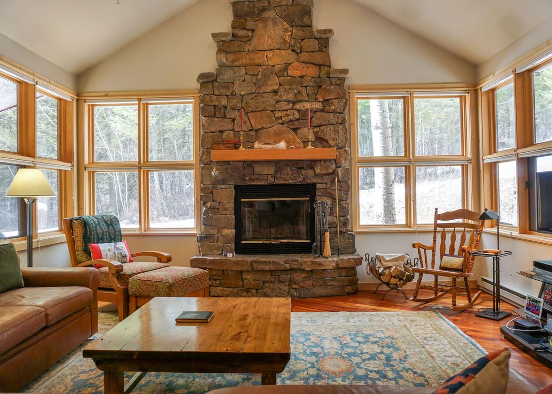 Inviting living room in Moose Creek 27 with a large stone fireplace and wooded views.