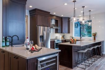 A modern kitchen with dark wood cabinets, stainless steel appliances, and a wine fridge.