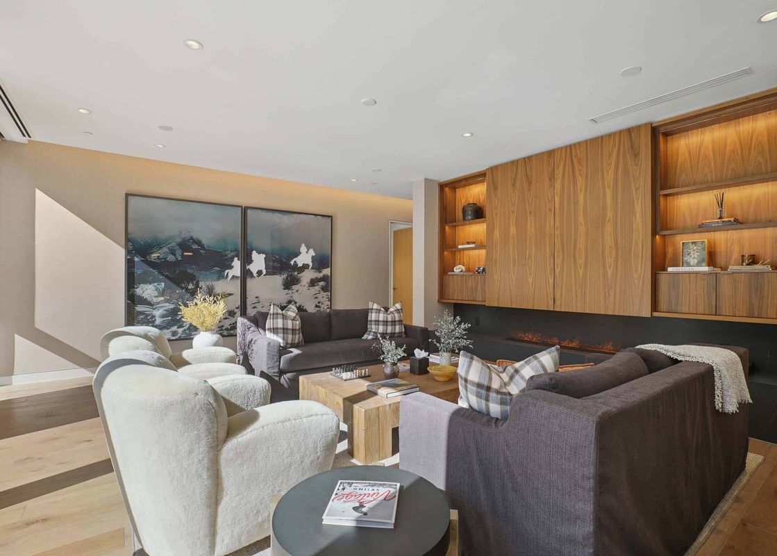 A modern living room in Founders Place 2303 with a fireplace, stylish seating, and abstract art.