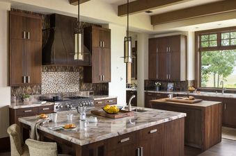 Modern spacious kitchen at Le Refuge with walnut cabinets, marble island, and custom range hood.
