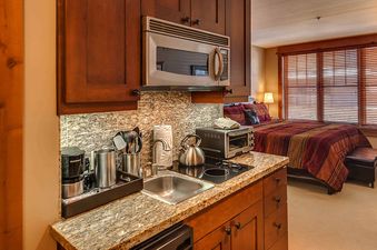 A small kitchen in a hotel room with a microwave, oven, and a sink