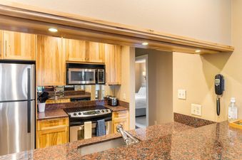 A kitchen with stainless steel appliances, wood cabinets, and granite countertops.