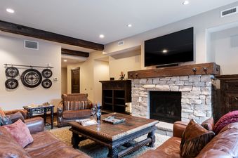 The comfortable and inviting living room at Silver Star 3101, featuring leather furniture, a stone fireplace, and a large flat-screen TV.