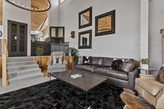 Living room at 2060 Solamere Drive with a brown leather sofa, a black rug, and three mirrors on the wall.