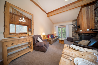 A spacious and inviting living area in Beaver Village 1134, featuring comfortable seating, a stone fireplace, and a large mirror reflecting the rustic decor.