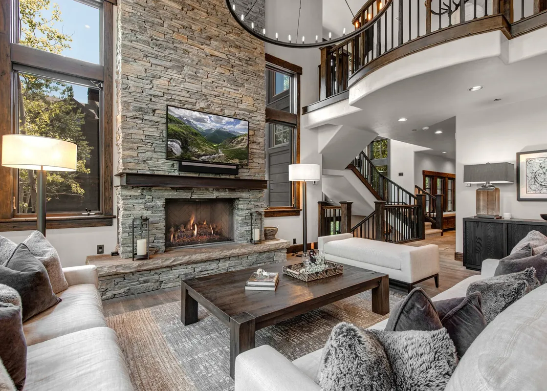 The living area at Weedon Ranch showcases a stunning stone fireplace, comfortable sofas, and large windows with an exterior view.