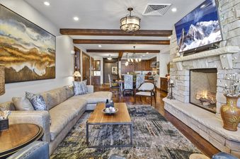 Cozy living room in Silver Strike Lodge 201 203 featuring a stone fireplace, leather sectional, and rustic wooden beams.