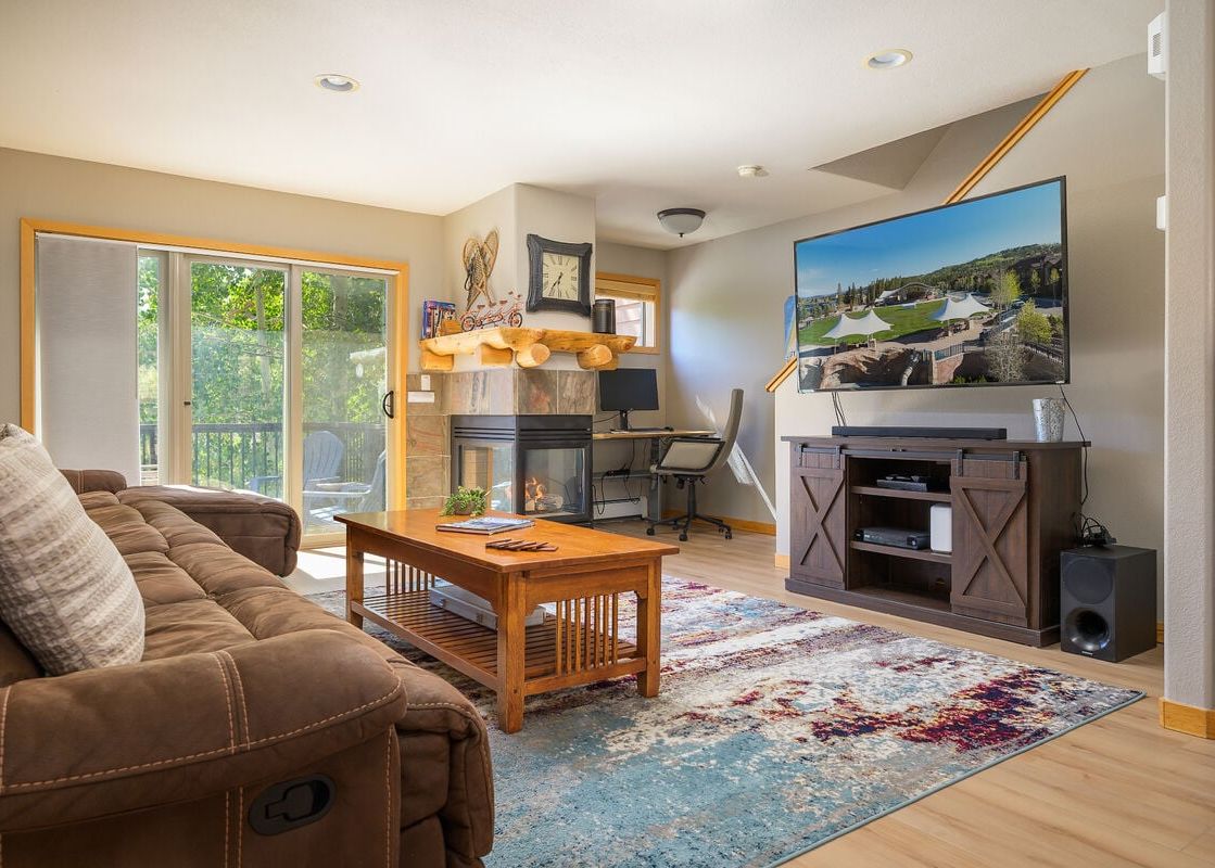 Cozy living area in Sawmill Station 217 featuring a brown sectional, a fireplace, and a wall-mounted TV.