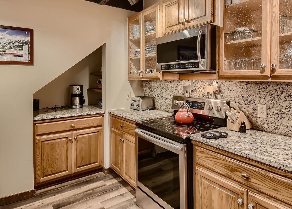 The kitchen at Breck Lodge features light wood cabinetry, granite countertops, and stainless steel appliances.