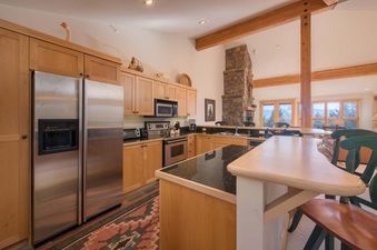 Well-equipped kitchen at Moose Creek 33 with wooden cabinets, stainless steel appliances, and a breakfast bar.