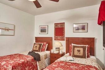 A cozy bedroom in Tensleep B 14 featuring two twin beds with rustic red quilts and moose-themed accent pillows.