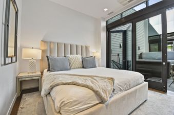 The luxurious bedroom at Parkite 34 boasts a plush bed, sophisticated decor, and large windows opening to an outdoor patio with a hot tub.