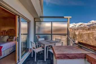 The Peaks Penthouse 752 features a balcony with an outdoor dining table and chairs, offering stunning mountain views.
