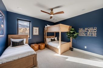 A stylish bedroom at 1725 Amanti Lago featuring navy blue walls, a single bed, a wooden bunk bed, and a motivational wall sign.