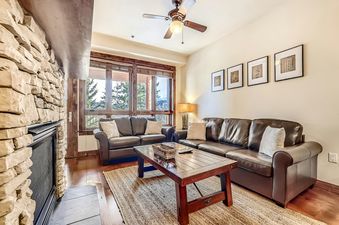 BlueSky Breckenridge 513's living room has a leather sofa, a coffee table, and a fireplace.
