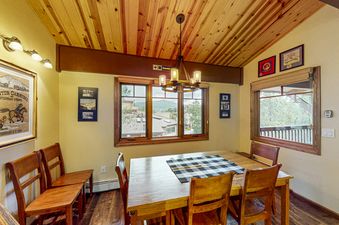 The Phoenix 122 dining area features a large wooden table with several chairs, bathed in natural light from the surrounding windows, with a light wood plank ceiling.
