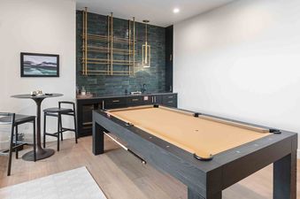 A modern games room with a billiards table and a wet bar area.