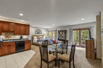 A wide shot of the studio apartment at Grand View on the Blue, featuring a dining area, living room, and a full kitchen.