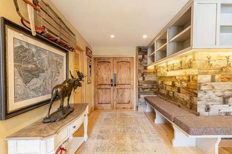 The entryway of Royal Plaza 403 features a wooden sled, ski map, moose sculpture, and a long wooden bench with storage.