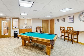 A spacious games room with a pool table, high-top chairs, and a coffee bar at Phoenix 215.