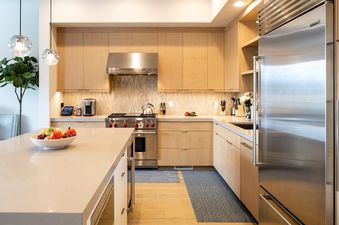 The modern kitchen in Moonlight Basin 83B Lodgeside features stainless steel appliances and light wood cabinetry, with a large island in the center of the room.