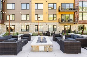 A patio with a fire pit and seating area in front of a building.