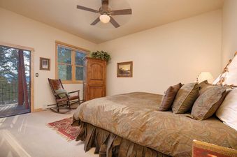 A comfortable bedroom at Moose Creek 31 with a wooden rocking chair, large armoire, and balcony access.