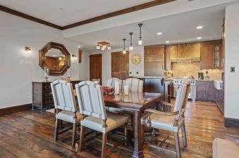 The dining area and kitchen in Arrowleaf Lodge 205, featuring a dark wood dining table with upholstered chairs, and a kitchen with wooden cabinetry and modern appliances.