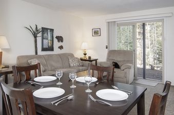 The dining area and living room with a large window and forest view at Hideaway Village Ladora 3.
