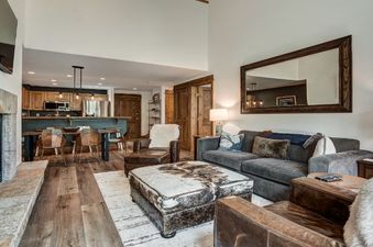 A cozy, rustic-chic living room with a fireplace and an open-concept kitchen and dining area.